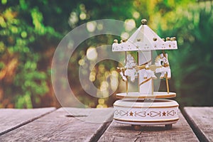 Vintage white carousel horses over wooden table outdoors