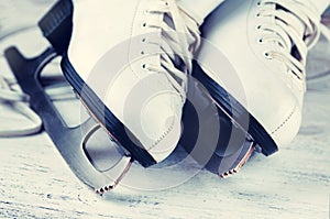 Vintage white female skates for figure skating, on a light wooden background.