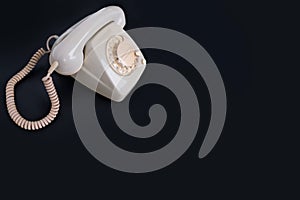 Vintage white telephone set with retro style dialing dial on black background, concept of old communication technologies, call
