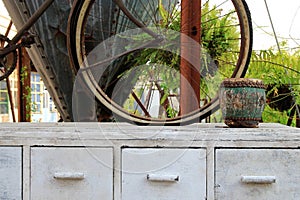 White wooden cabinet with old drum and wheel of bicycle.