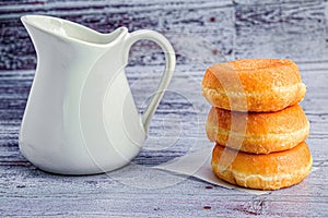 Vintage white wooden table with delicious donuts and a pitcher of milk atop