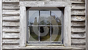 Vintage window with antique glass set in weathered wood plank wall