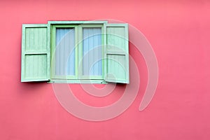 Vintage window with green shutters on pink wall