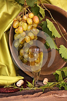 Vintage wine glass against background cluster of grapes and coop