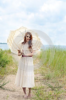 Vintage woman with parasol by the ocean