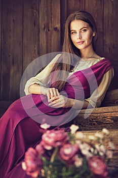 Vintage Woman Portrait blossom Flower in Basket. Beauty Model happy smiling over dark Wooden Background Pink Dress