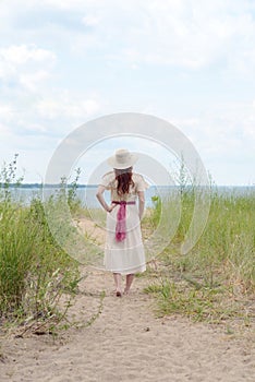 Vintage woman wearing hat walking on beach path