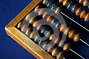 Vintage wooden abacus close up. Counting wooden knuckles. Part of the old end of the abacus on a dark blue background