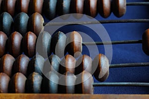 Vintage wooden abacus close up. Counting wooden knuckles. Part of the old end of the abacus on a dark blue background