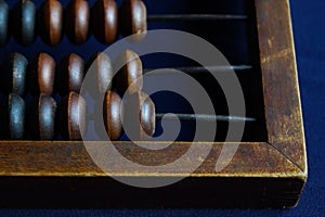 Vintage wooden abacus close up. Counting wooden knuckles. Part of the old end of the abacus on a dark blue background