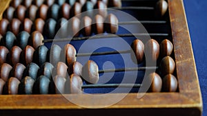 Vintage wooden abacus close up. Counting wooden knuckles. Part of the old end of the abacus on a dark blue background.
