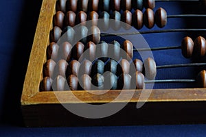 Vintage wooden abacus close up. Counting wooden knuckles. Part of the old end of the abacus on a dark blue background