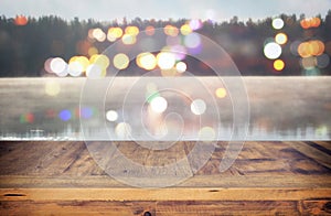 vintage wooden board table in front of abstract photo of misty and foggy lake at morning/evening.