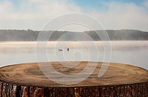 vintage wooden board table in front of abstract photo of misty and foggy lake at morning/evening.