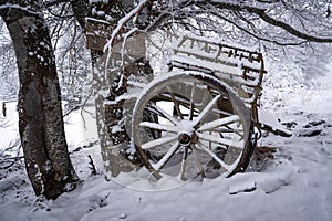Vintage wooden carriage under snow in forest