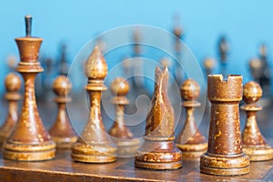 Vintage wooden chess pieces on an old chessboard.