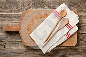 Vintage wooden cutting board, spoons and kitchen towel on wooden table