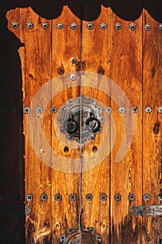Vintage wooden door with intricate iron details including rivets and knobs.