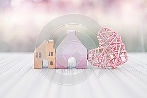 Vintage wooden miniature house with pink wooden heart design over blurred background