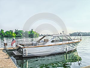 Vintage wooden seaskiff moored at the dock on a sunny day at the lake with bumpers down and American flag flying