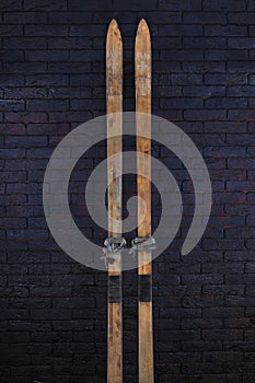 vintage wooden skis, black brick wall