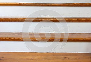 Vintage wooden stair with brown plank tread and white riser. Wood shelf on white painted wall