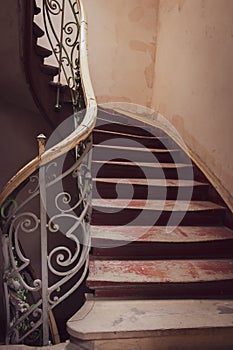 Vintage wooden staircase with iron rail. Old circular stairway in abandoned historical building. Spiral stairway.
