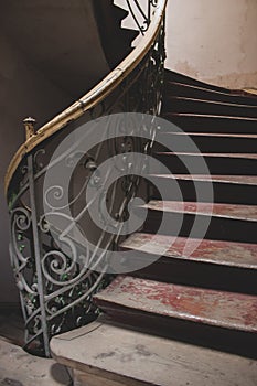 Vintage wooden staircase with iron rail. Old circular stairway in abandoned historical building. Spiral stairway.