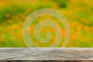 Vintage wooden tabletop on blurred yellow garden background, for product display