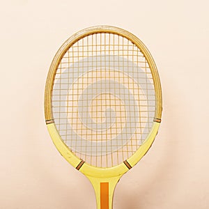 Vintage wooden tennis racket against pink wall