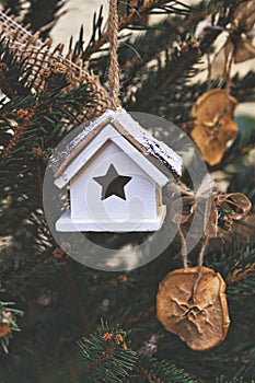 Vintage wooden toy house on Christmas tree. Natural Xmas ornaments for Christmas decoration, zero-waste