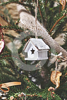 Vintage wooden toy house on Christmas tree. Natural Xmas ornaments for Christmas tree, zero-waste