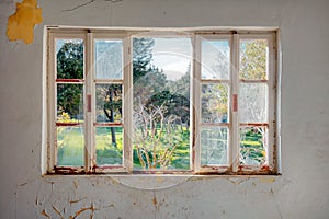 Vintage wooden window frame with broken glass looking through a green meadow field. of an Interior of a desolated house photo