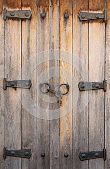 Vintage wooden window shutters with rusty iron hinges and padlock on chain in Nesebar. Closed rustic wooden shutters