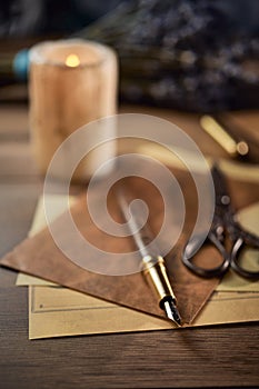 Vintage writing utensils on a wooden table, old watch, papers, letters, envelopes and scissors