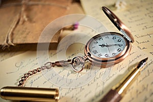 Vintage writing utensils on a wooden table, old watch, papers, letters, envelopes and scissors