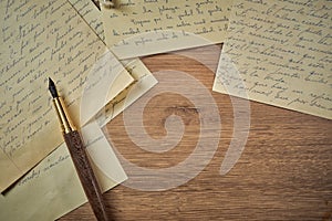 Vintage writing utensils on a wooden table, old watch, papers, letters, envelopes and scissors