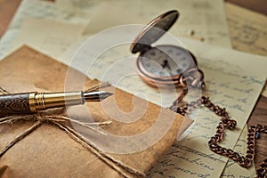 Vintage writing utensils on a wooden table, old watch, papers, letters, envelopes and scissors