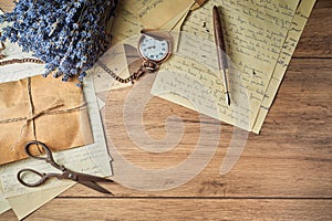 Vintage writing utensils on a wooden table, old watch, papers, letters, envelopes and scissors