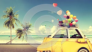 Vintage yellow car with heart colorful balloon on beach