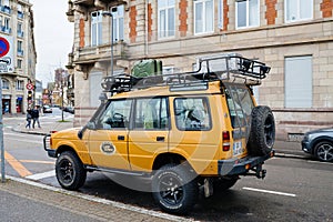 vintage yellow Land Rover Defender Camel Trophy parked in city