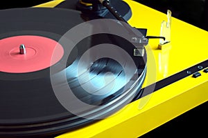 Vintage yellow turntable plays vinyl record closeup