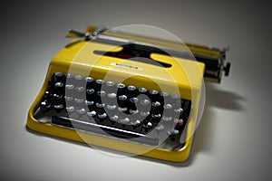 Vintage yellow typewriter in evocative spotligh