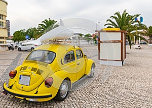 Vintage yellow Volkswagen beetle car with a dolphin figure on a cobblestone road