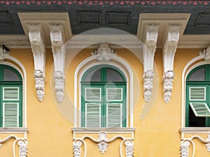 Vintage yellow wall with green window and white cement sculpture arch, architecture concept