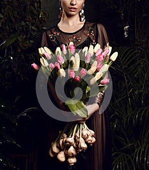 Vintage young woman with big bouquet of fresh spring white tulip flowers. Spring style green leaves