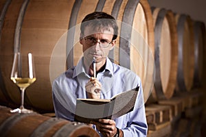 Vintner in cellar analyzing white wine.