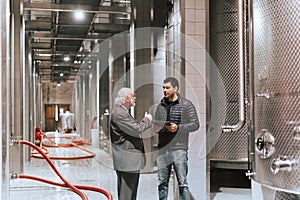 Vintner and client walking through a wine production plant