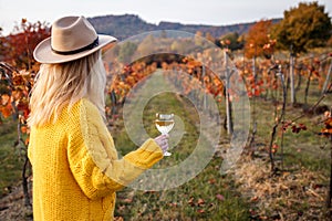 Vintner enjoying white wine in her vineyard at autumn