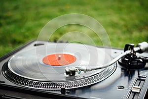 Vinyl disc playing on turntable, green grass background